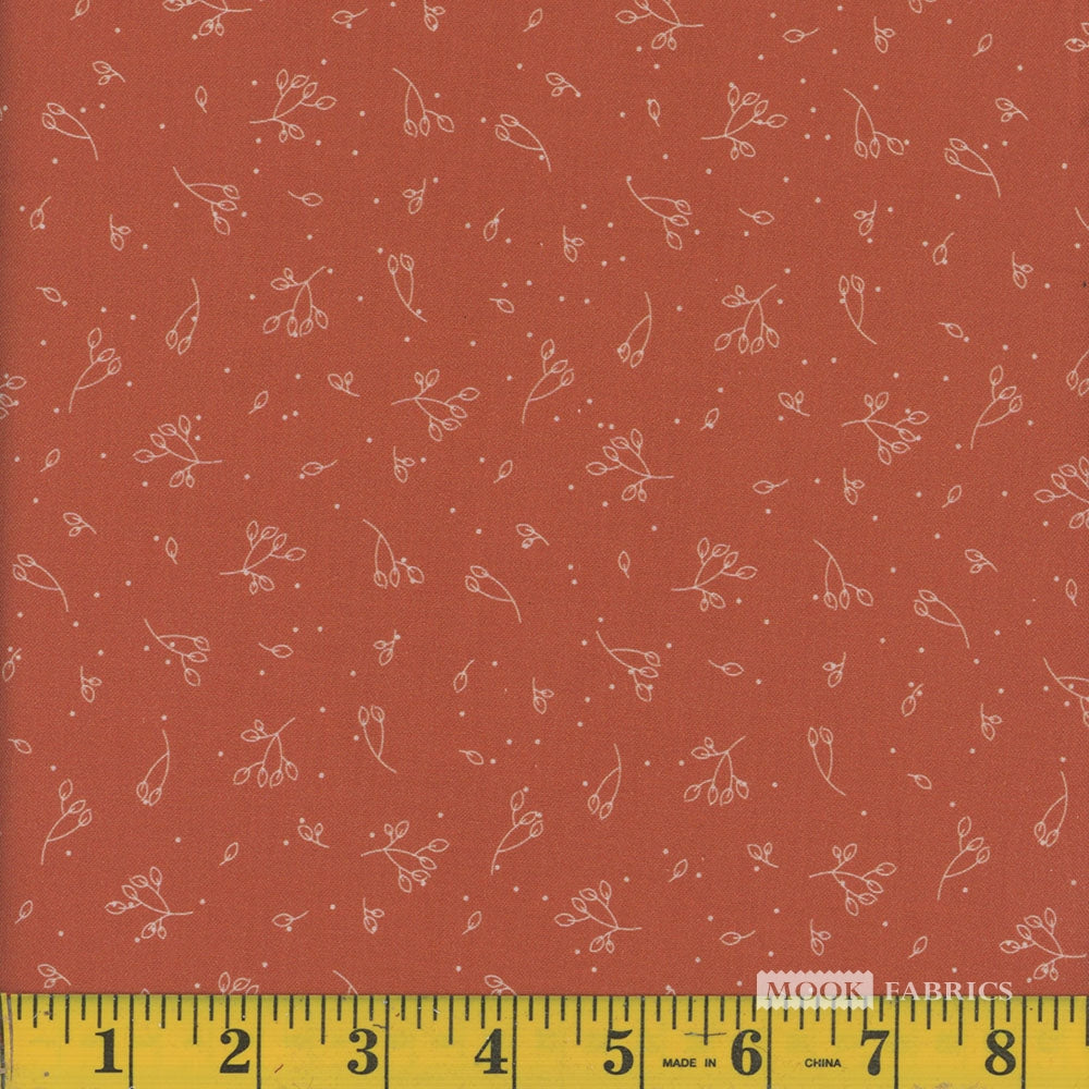 Dark orange fabric with small white floral pattern and a ruler at the bottom for scale.
