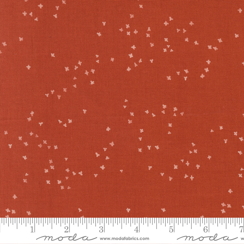 Red fabric with small white floral patterns and a ruler at the bottom