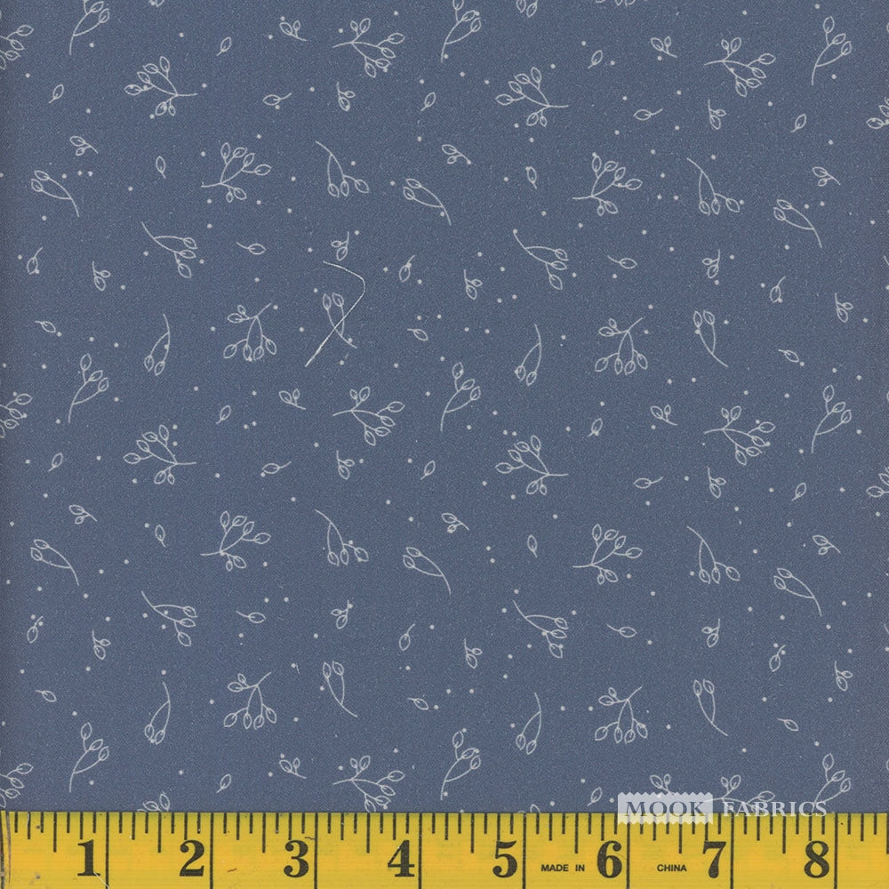 Fabric with small white floral pattern on a blue background, measured by a yellow ruler.