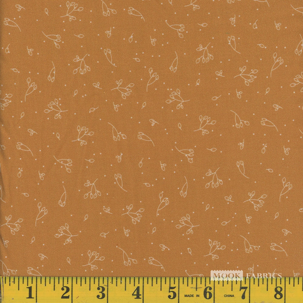 Mustard yellow  fabric with small white floral pattern and a ruler at the bottom for scale.