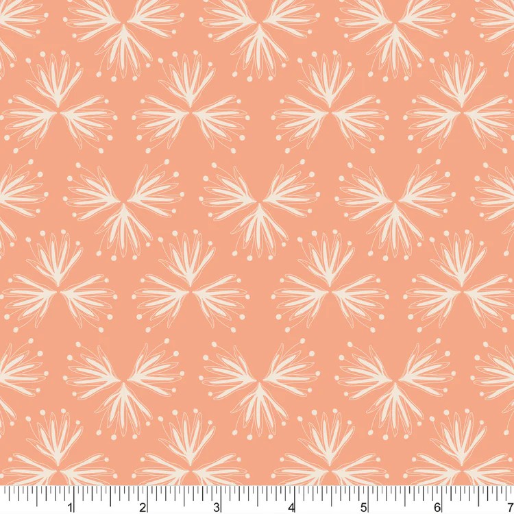 White floral pattern on a peach-colored fabric with a ruler for scale.